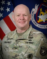 man in uniform standing in front of flags.