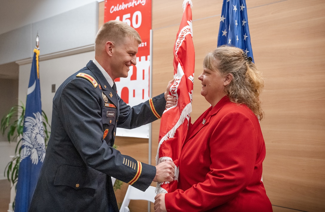 Lt. Col. Andrew Johannes, hands the U.S. Army Corps Of Engineers, Charleston District guidon to Lisa Metheney, Deputy District Engineer for Programs and Project Management, during a change of command ceremony.  Johannes became the district’s 89th commander, taking over for outgoing commander Lt. Col. Rachel Honderd.