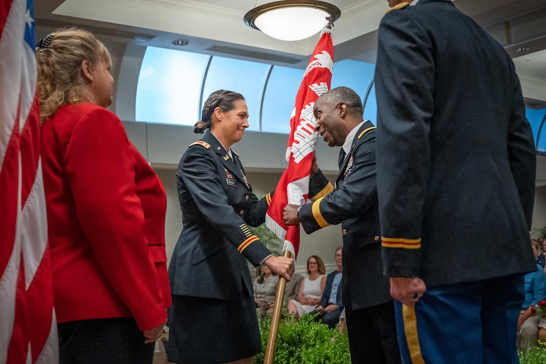 Man and woman on stage exchanging flags.