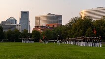 Marines of Company A, and Company B stand at ceremonial at ease as the Marines of the U.S. Marine Corps Silent Drill Platoon conduct a “Bursting Bomb” during a Tuesday Sunset Parade at the Marine Corps War Memorial, Arlington, VA, June 15 2021.