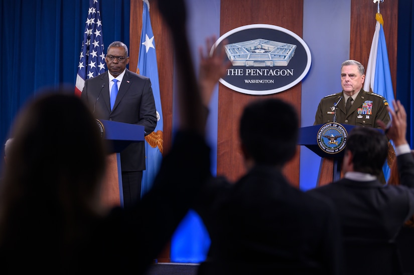 Secretary of Defense and chairman of the Joint Chiefs of Staff stand at lecterns.