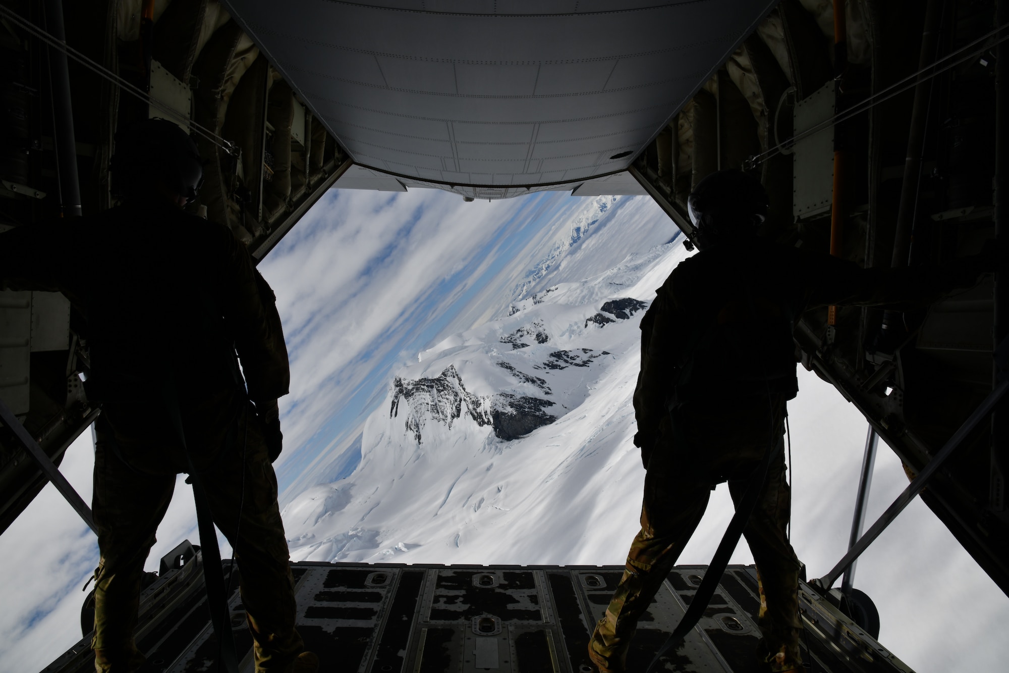 Tech. Sgt. Jacob Fountain (left) and Master Sgt. Gary Bryant (right), 815th Airlift Squadron loadmasters, hold on after opening the cargo door ramp while the pilots conduct low-level tactical flight training patterns during a training exercise at Joint Base Elmendorf-Richardson, Alaska, July 13-16, 2021. The terrain of the mountain, valleys and along with the colder temperatures provided a different challenge for the low-level flights, which were an effective tactic in training for hostile environments. (U.S. Air Force photo by Master Sgt. Jessica Kendziorek)