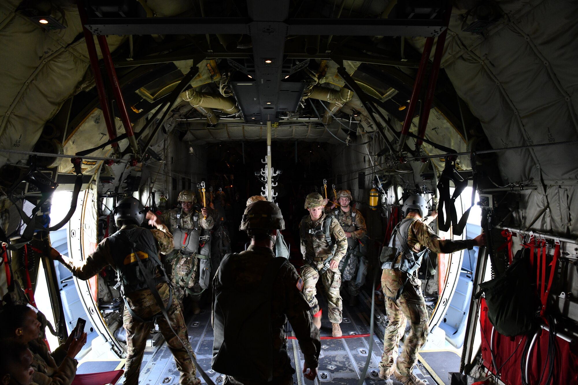 Master Sgt. Gary Bryant (left) and Tech. Sgt. Jacob Fountain (right), 815th Airlift Squadron loadmasters, watch outside the open troop doors until given the signal from the pilots to pass off the opened doors to the jumpmasters from the 4th Infantry Brigade Combat Team Airborne, 25th Infantry Division, who will release the paratroopers out of the C-130J Super Hercules during a training exercise, July 13-16, 2021. (U.S. Air Force photo by Master Sgt. Jessica Kendziorek)
