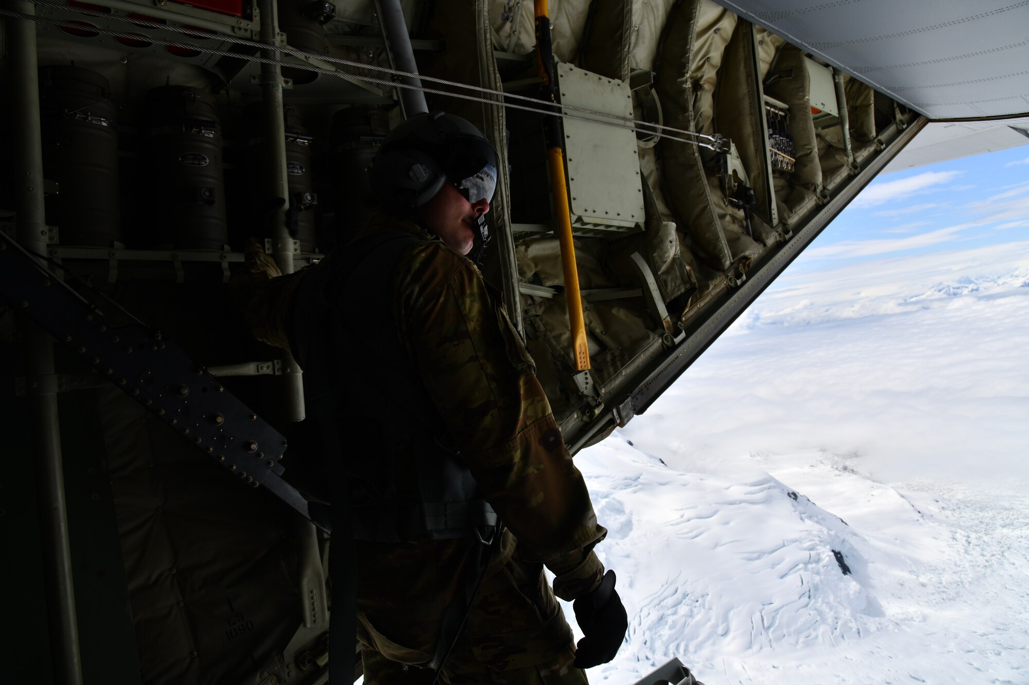 Tech. Sgt. Jacob Fountain, 815th Airlift Squadron loadmaster, holds on after opening the cargo door ramp while the pilots conduct low-level tactical flight training patterns during a training exercise at Joint Base Elmendorf-Richardson, Alaska, July 13-16, 2021. The terrain of the mountain, valleys and along with the colder temperatures provided a different challenge for the low-level flights, which were an effective tactic in training for hostile environments.  (U.S. Air Force photo by Master Sgt. Jessica Kendziorek)