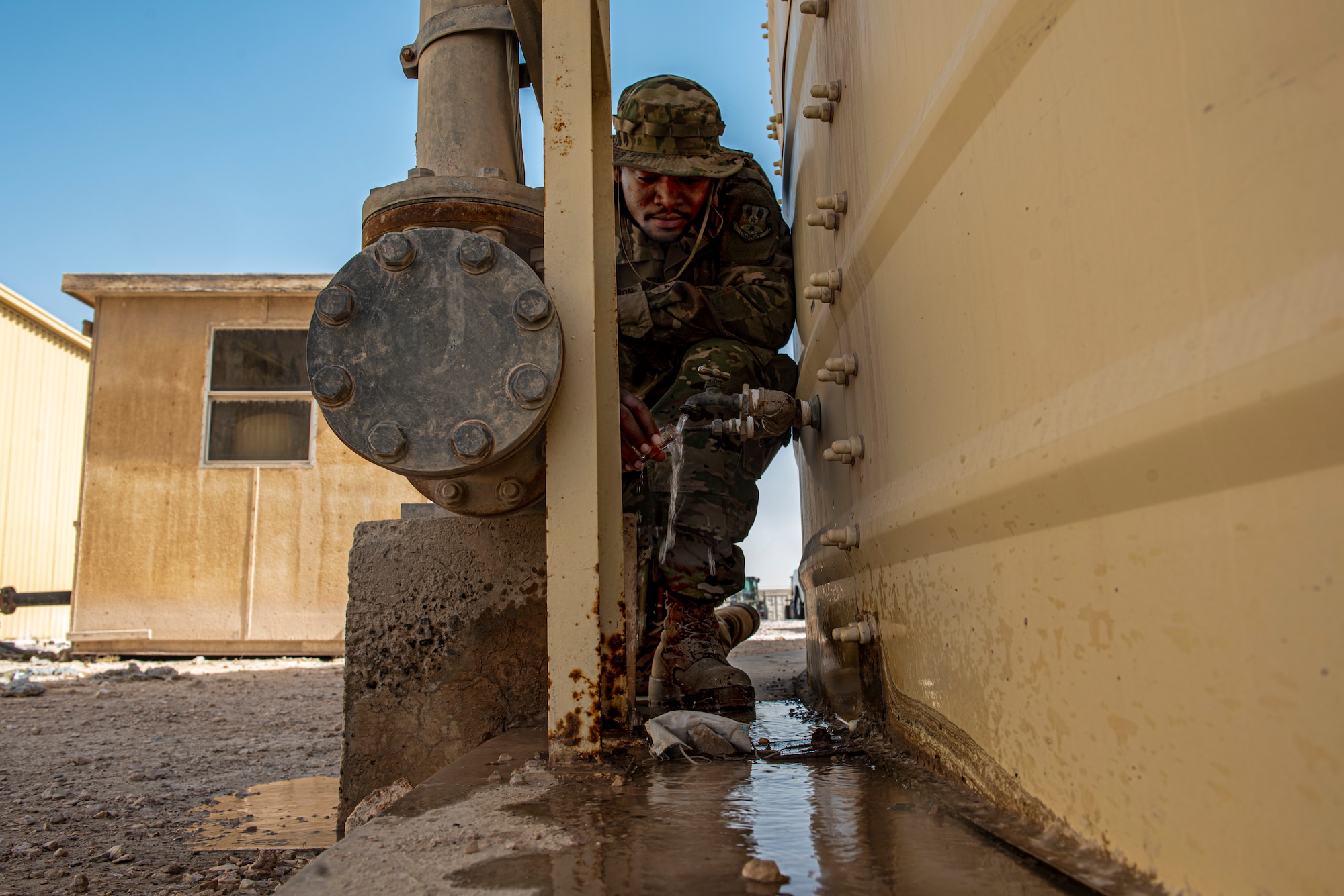 Airman 1st Class Brandon Johnson, 379th Expeditionary Civil Engineer Squadron water & fuel systems maintenance journeyman, collects a daily water sample to ensure quality standards are being met June 16, 2021 at Al Udeid Air Base, Qatar.