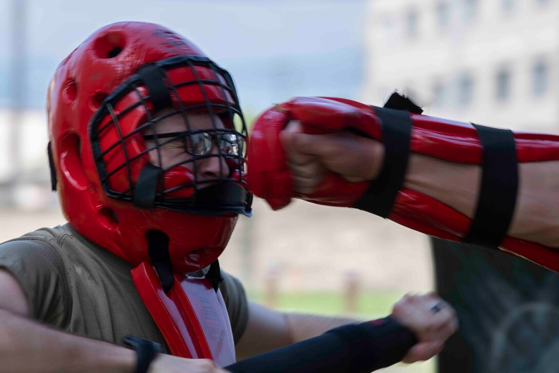 Senior Airman Scott Madrigal-Silver, 374th Civil Engineer Squadron geobase technician, braces for the punch from Senior Airman Tyler Gutierrez, 374th Security Forces Squadron training instructor, during a 374th Mission Support Group training day at Yokota Air Base, Japan, July 21, 2021.