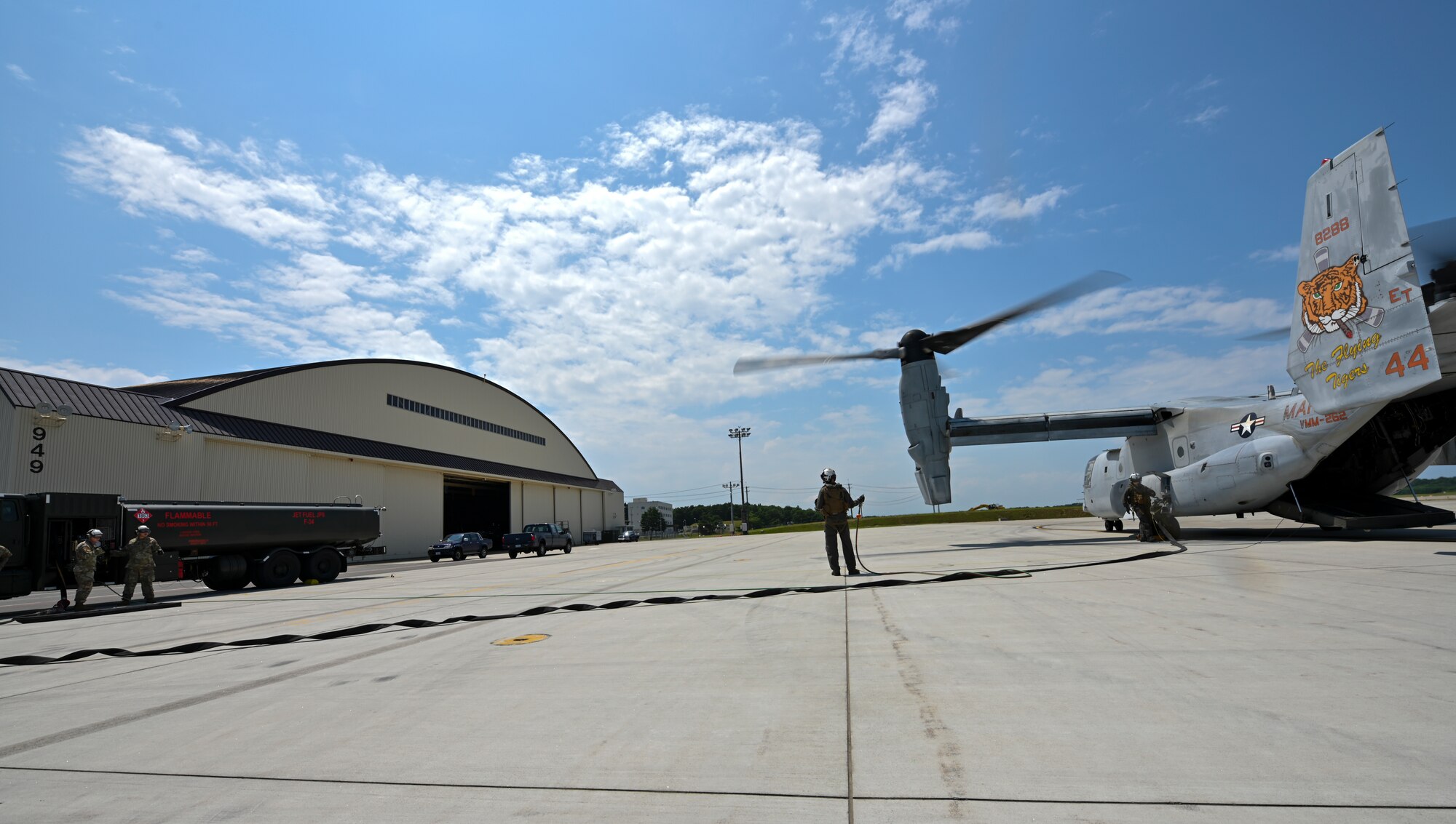 A tiltrotor aircraft with its engines running is parked on a flight line.