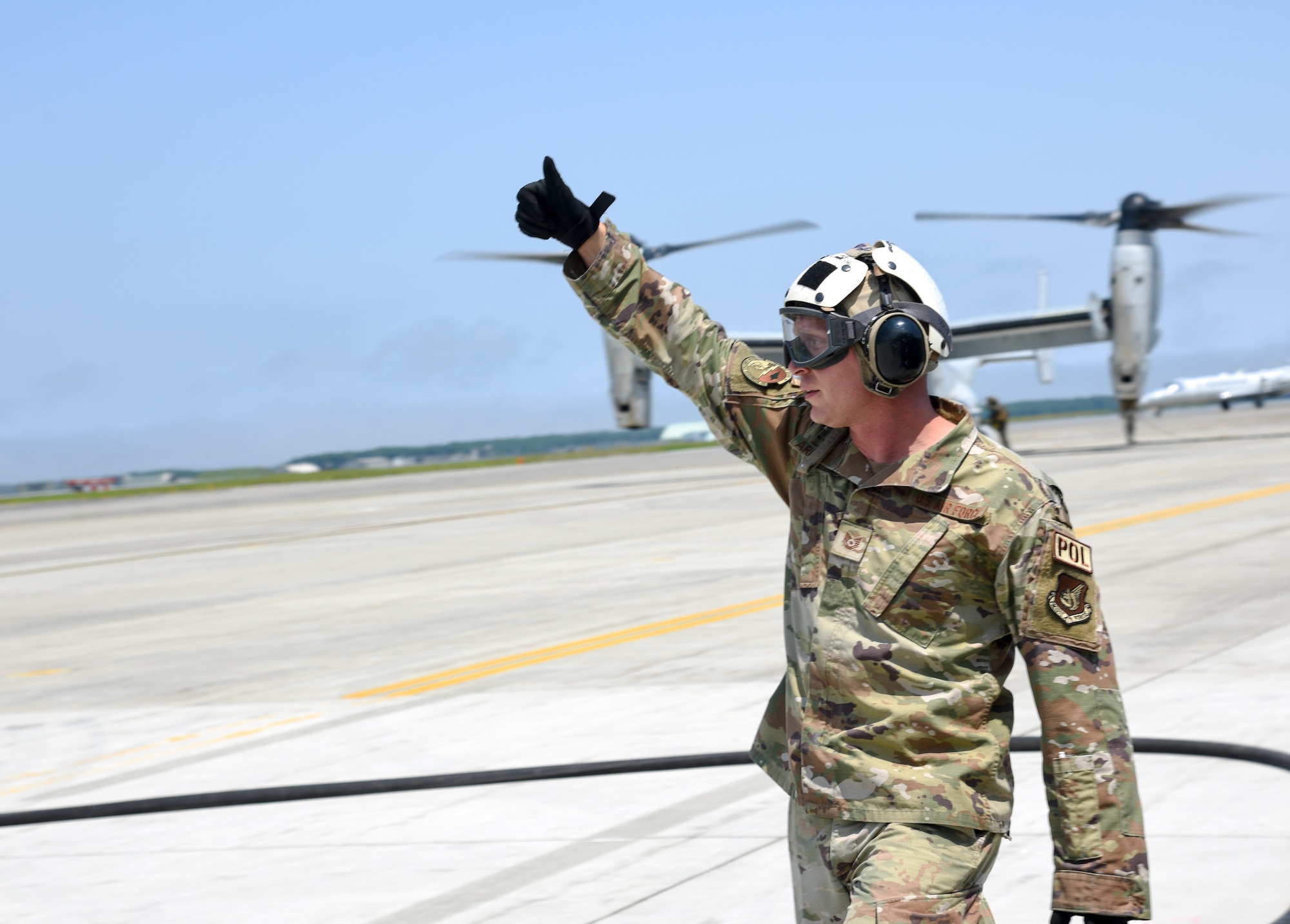 An Airman raises his arm above his head as he gives a thumbs up.