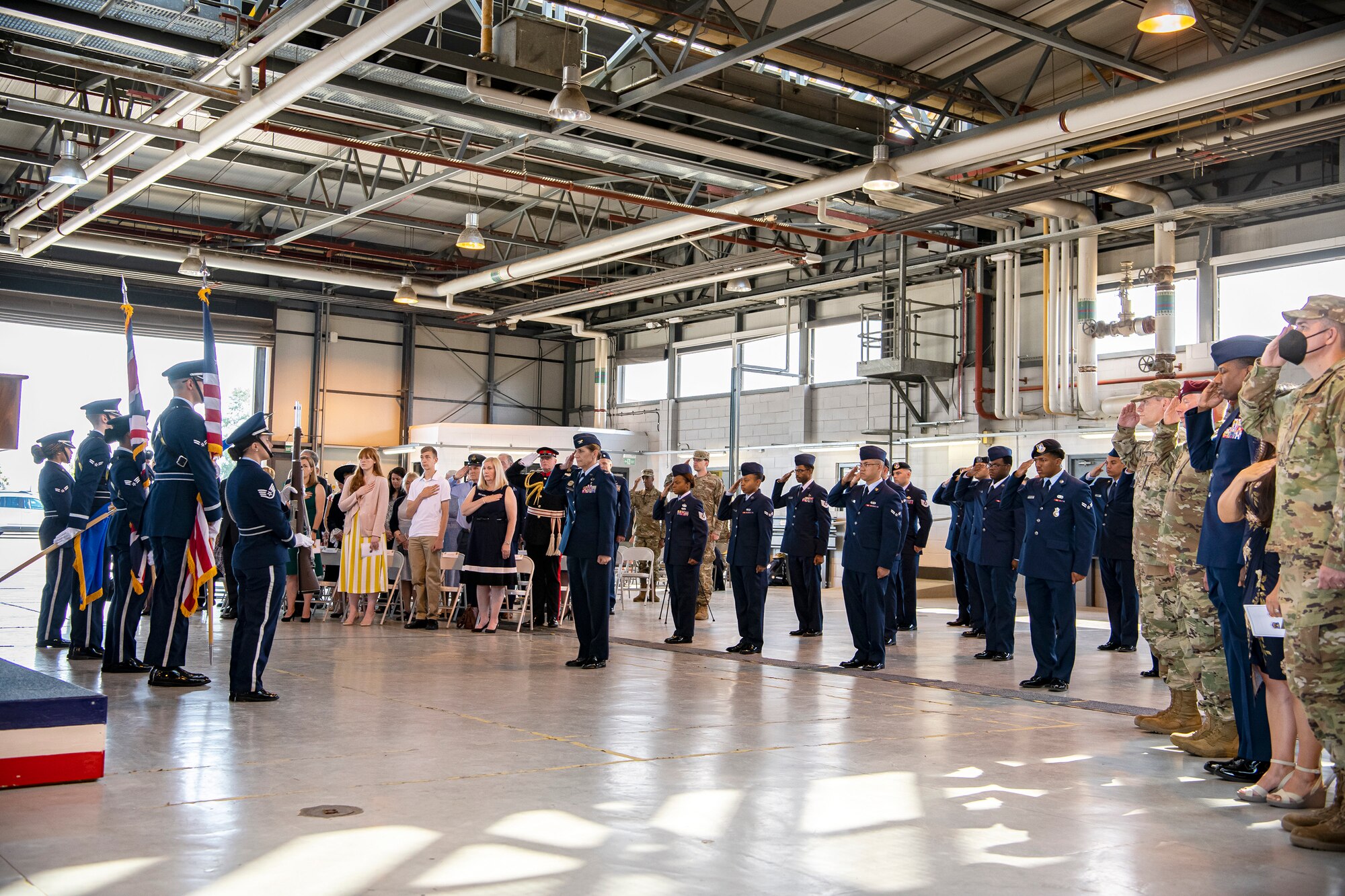 Airmen from the 501st Combat Support Wing and guests salute during the playing of the national anthem at RAF Alconbury, England, July 20, 2021. The ceremony is a military tradition that represents a formal transfer of a unit’s authority and responsibility from one commander to another. (U.S. Air Force photo by Senior Airman Eugene Oliver)