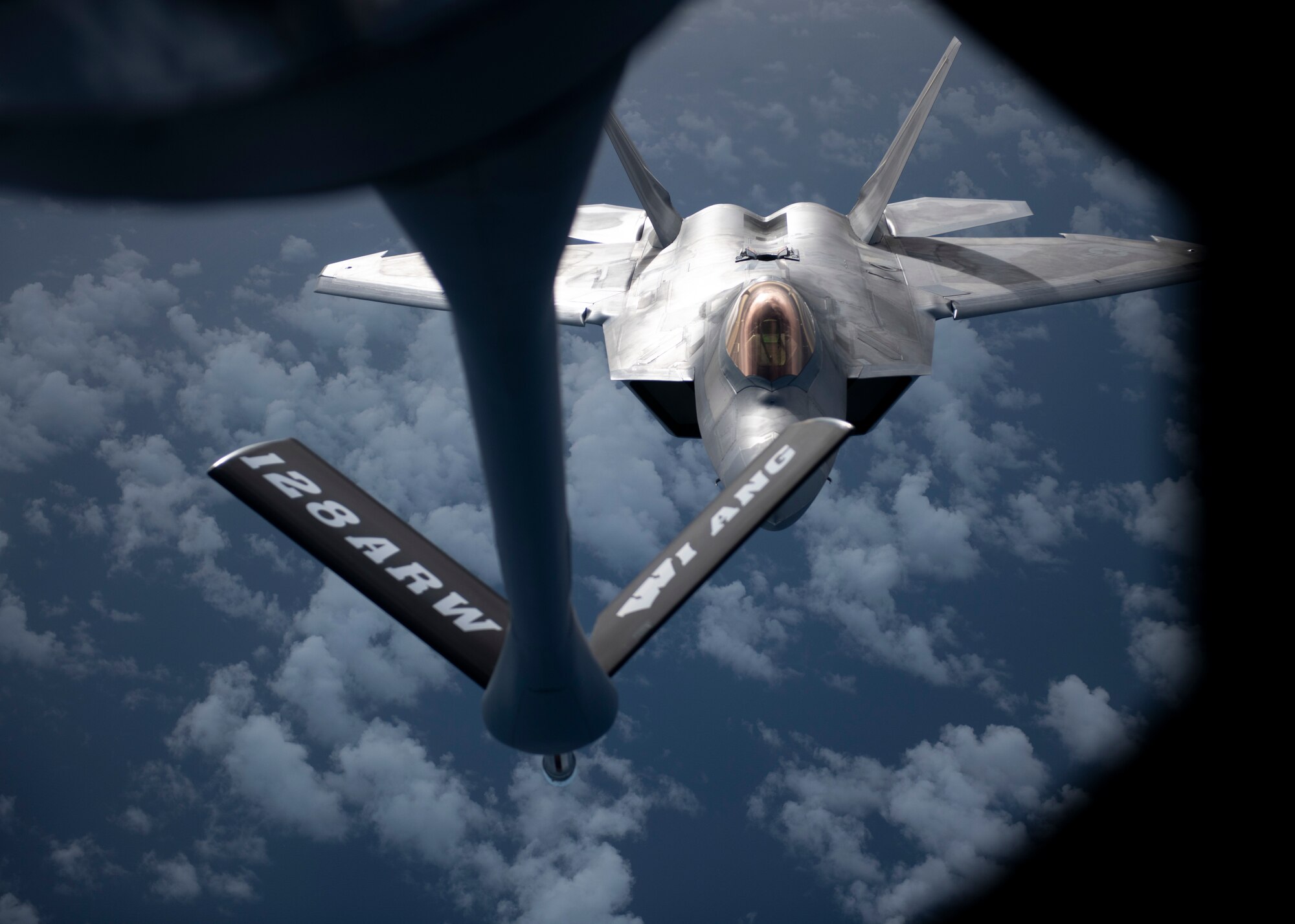 A fighter jet flies behind a refueling boom