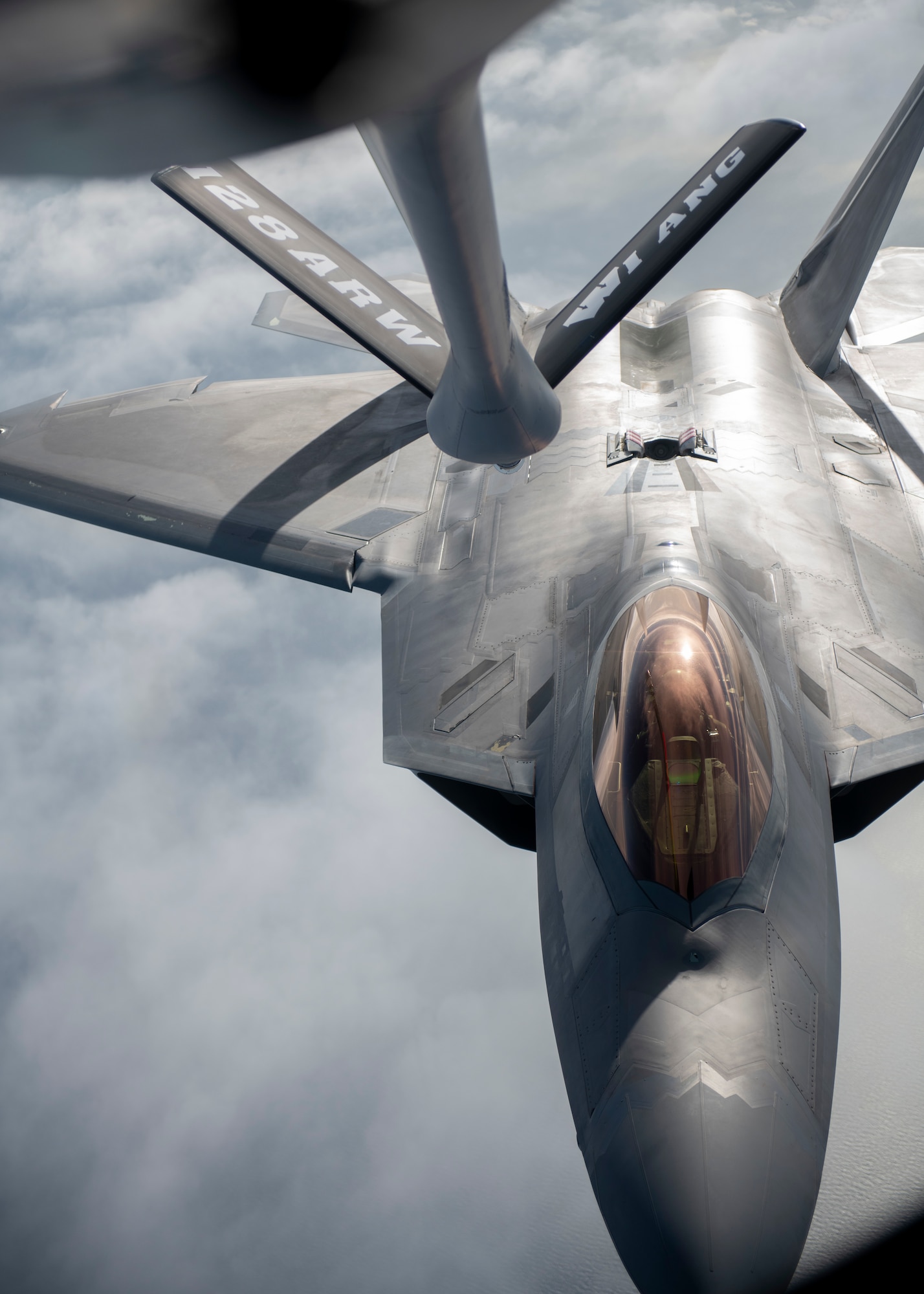 A fighter jet flies behind a refueling boom