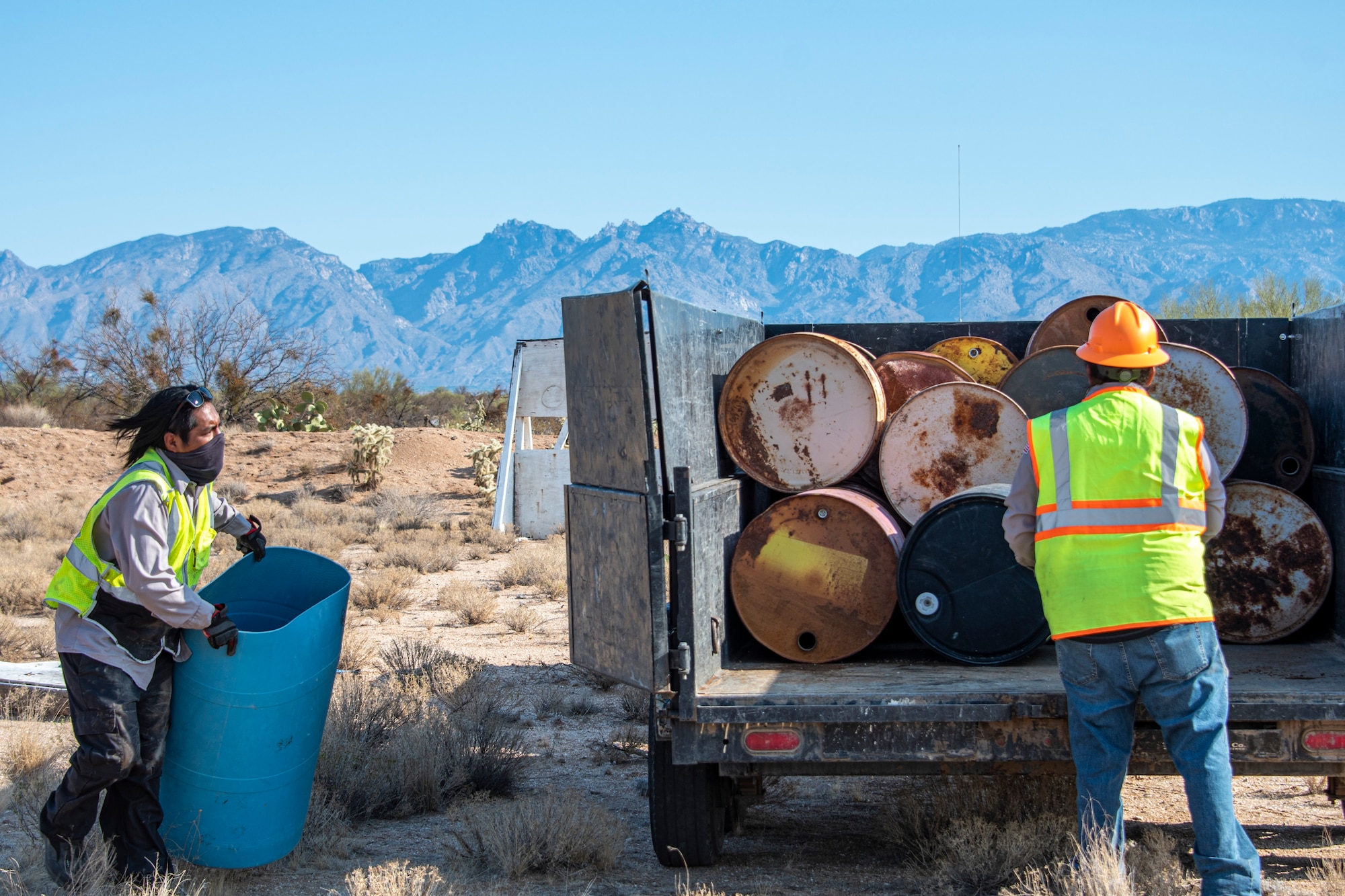 A photo of people loading drums into a truck.