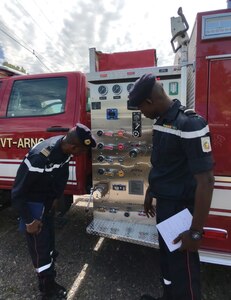 Two members of Senegal's National Fire Brigade examine a Vermont National Guard fire response vehicle on July 12, 2021 at Camp Johnson, Vermont. From July 11-21, delegates from Senegal’s National Fire Brigade (Brigade Nationale des Sapeurs-Pompiers) visited Vermont as part of the National Guard’s State Partnership Program (U.S. Army National Guard photo by Joshua T. Cohen)