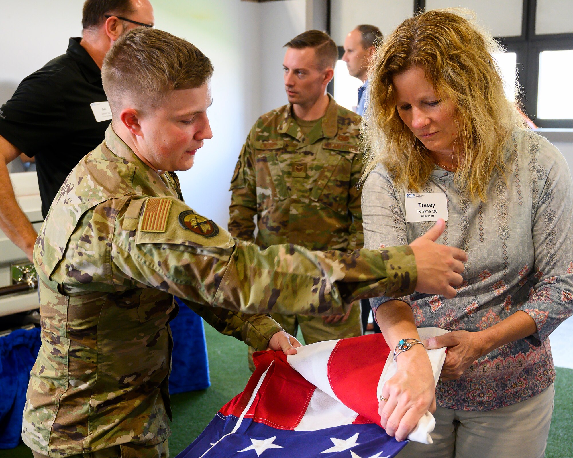 Airman 1st Class Blake Cassick of Wright-Patterson Air Force Base’s Honor Guard shows Tracey Tomme how to ceremoniously fold the flag July 14. A Leadership Dayton program member, Tomme was part of the group tour allowing participants to learn about the base’s capabilities and its community contributions. (U.S. Air Force photo by R.J. Oriez)