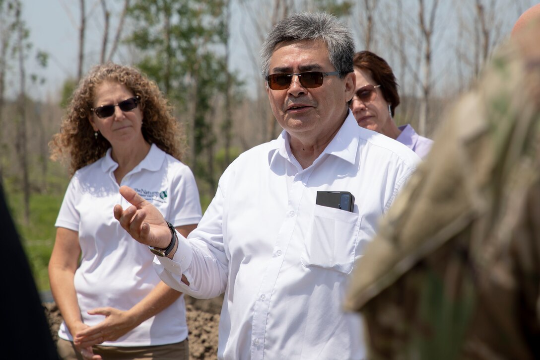 A man in a white shirt talks to a group of people.