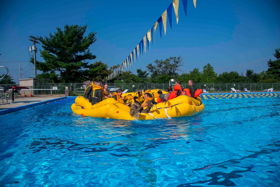 Airmen sit in a raft in an outdoor pool.