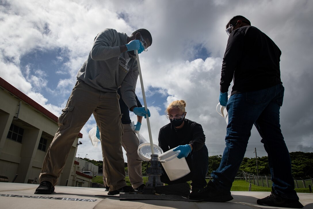 Xavier Taylor, left, and Kayla Maholy, center, environmental protection assistants with Marine Corps Installations Pacific (MCIPAC), Marine Corps Base Camp Smedley D. Butler (MCBB) and U.S. Marine Corps Lance Cpl. Cameron Whitman, right, a hazardous waste technician with Headquarters & Support Battalion, MCIPAC-MCBB, draw perfluoroalkyl and polyfluoroalkyl substances (PFAS) Effluent Treatment System (PETS) treated water samples on Marine Corps Air Station (MCAS) Futenma, Okinawa, Japan, July 19, 2021. MCIPAC and MCAS Futenma hosted visitors from the Okinawa Prefectural Government (OPG), Ginowan City, the Okinawa Defense Bureau (ODB) and the Ministry of Environment to observe MCIPAC environmental branch personnel draw PETS treated water samples. Samples were provided to the OPG and ODB to enable them to test the water to demonstrate the effectiveness and safety of PETS. (U.S. Marine Corps photo by Lance Cpl. Isaac W. Munce)
