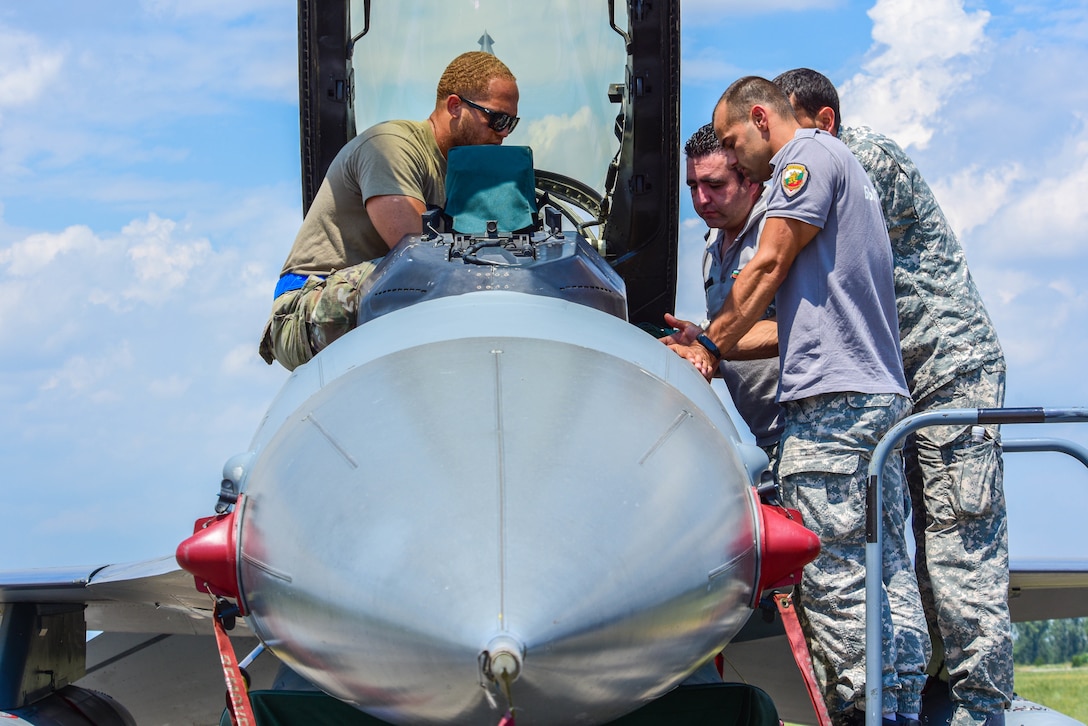 Senior Airman Alexander Smalls, 31st Maintenance Squadron aircrew egress journeyman, left, teaches Bulgarian air force members egress procedures during exercise Thracian Star 21 at Graf Ignatievo Air Base, Bulgaria, July 20, 2021. Thracian Star 21 is a multilateral training exercise with the Bulgarian air force that increases operational capacity, capability and interoperability with Bulgaria. (U.S. Air Force photo by Airman 1st Class Brooke Moeder)