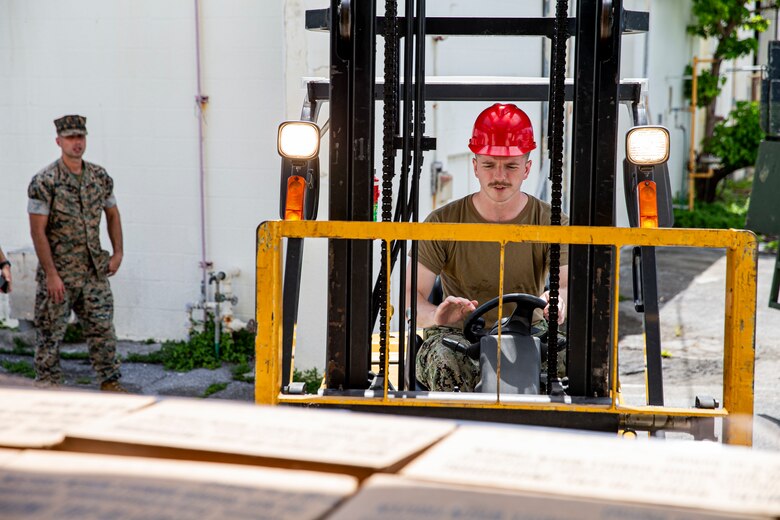 A U.S. Navy sailor with Camp Foster Camp Services operates a forklift to provide meals, ready to eat (MRE’s) to units on Camp Lester, Okinawa, Japan, July 19, 2021. In preparation for Typhoon In-Fa, Camp Foster Camp Services provide units with MRE’s, base preparation services, sandbags, and bulk trash storage to keep service members safe and prepared during typhoon season in Okinawa. (U.S. Marine Corps photo by Lance Cpl. Alex Fairchild)