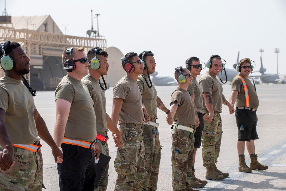Airmen holding hands in a line on the flight line