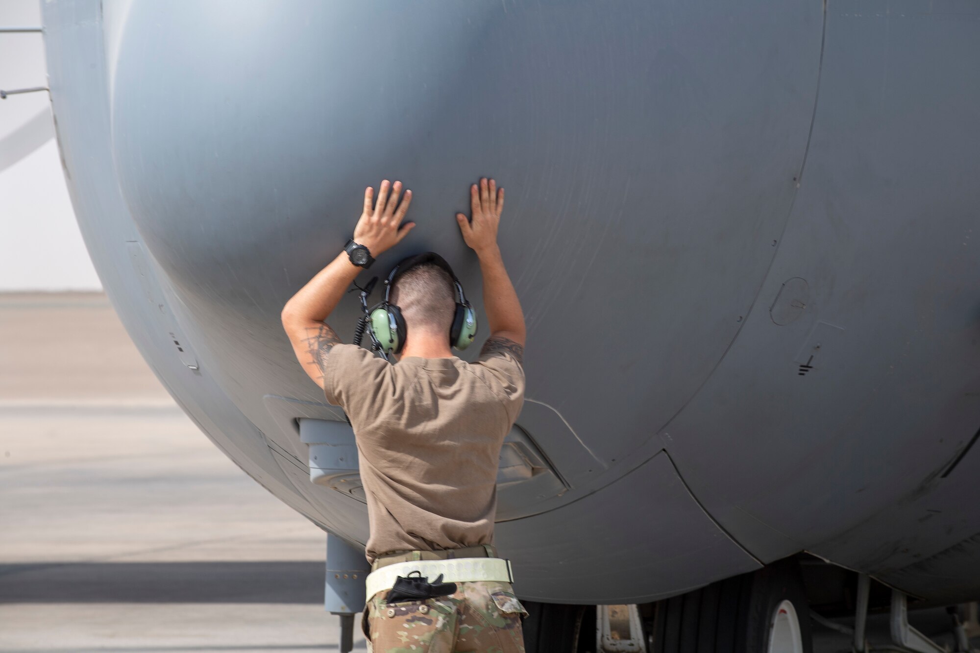 Airman putting hands on an EC-130H Compass Call aircraft