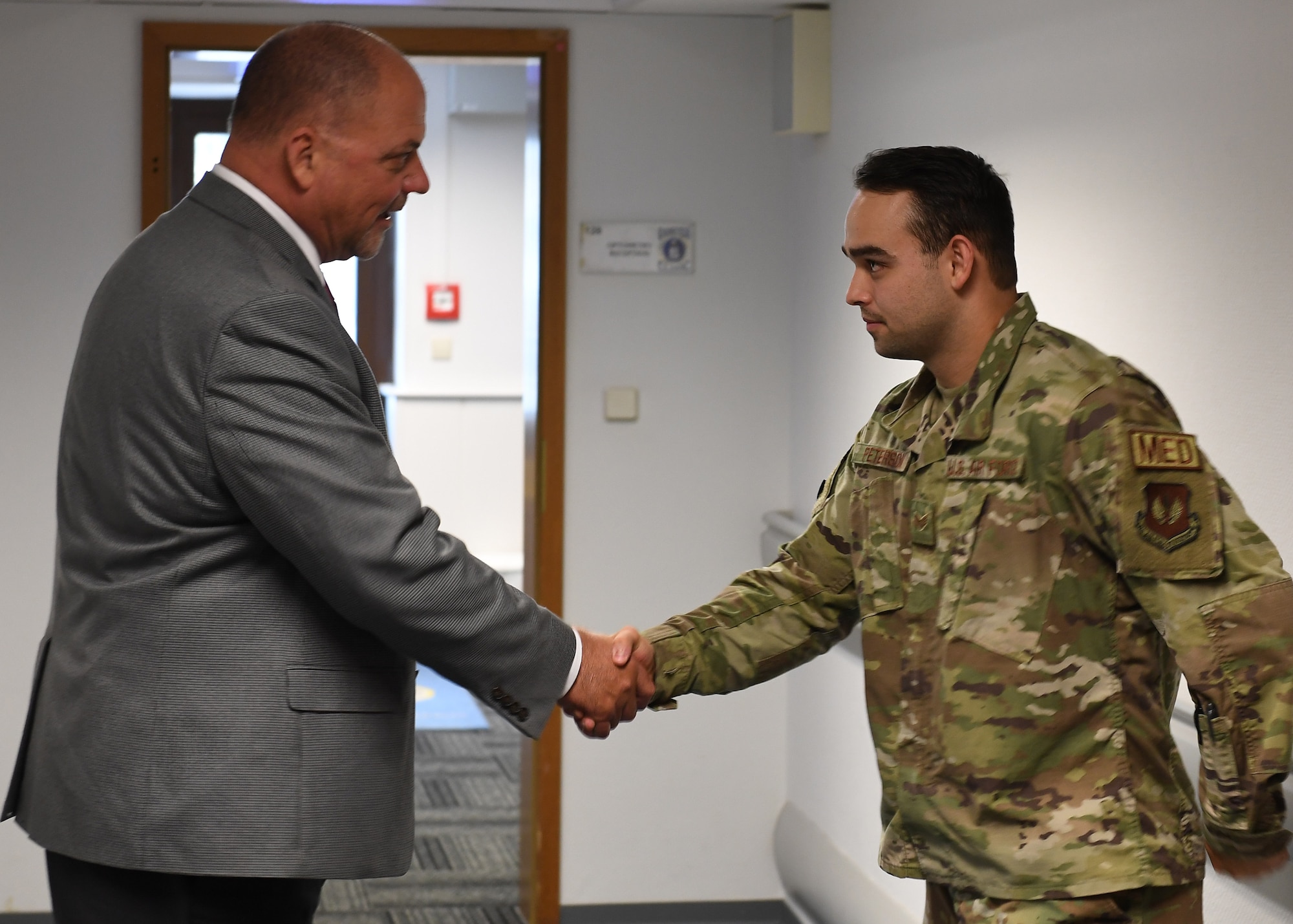 Scott C. Lockard, 86th Airlift Wing vice director, shakes Senior Airman Alexander Peterson's, 86th Medical Group human performance and ophthalmic technician, hand.