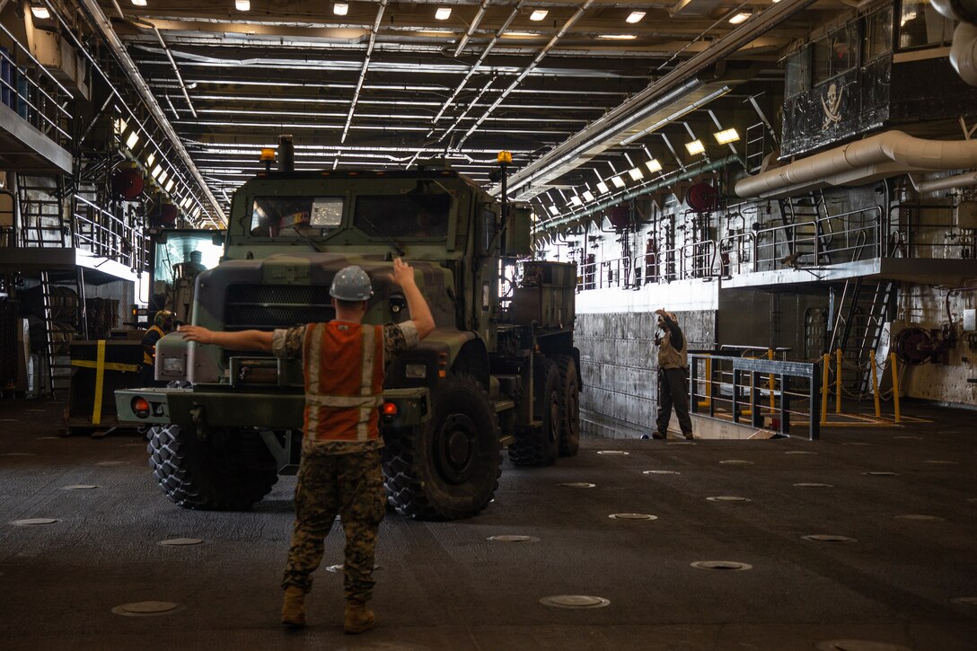 U.S. Marines and Sailors load tactical vehicles from the USS Arlington (LPD-24) onto an air cushion, landing craft during Defense Support of Civil Authorities (DSCA) mission rehearsals at Naval Base Norfolk, Virginia, July 22, 2021. Marines and Sailors with the II Marine Expeditionary Force Maritime DSCA Task Force, commanded by Combat Logistics Battalion 22, and Sailors aboard the USS Arlington conducted a destructive weather mission rehearsal loading exercise to prepare and rehearse for a future DSCA mission during the 2021 hurricane season. (U.S. Marine Corps photo by Lance Cpl. Scott Jenkins)