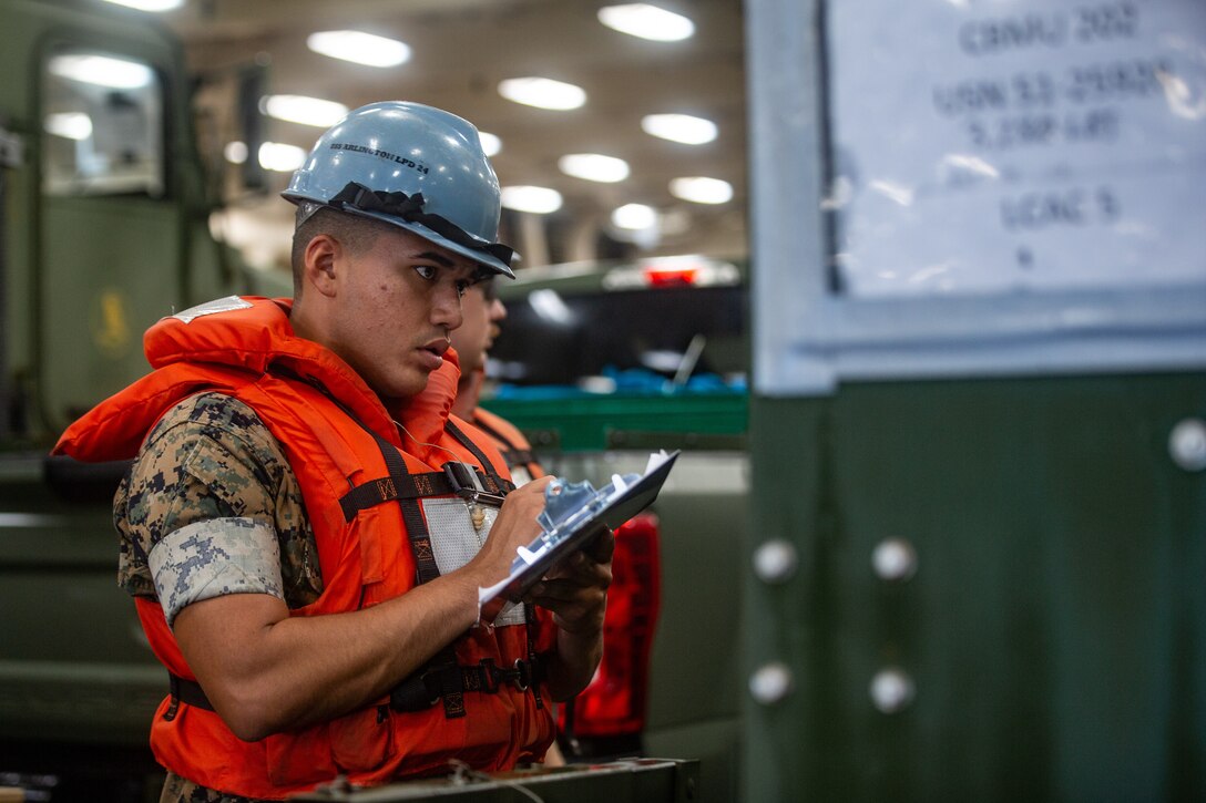 U.S. Marine Corps Lance Cpl. Jonas Cantu checks the vehicle loading plan aboard the USS Arlington (LPD-24) during Defense Support of Civil Authorities (DSCA) mission rehearsals at Naval Base Norfolk, Virginia, July 21, 2021. Marines and Sailors with the II Marine Expeditionary Force Maritime DSCA Task Force, commanded by Combat Logistics Battalion 22, and Sailors aboard the USS Arlington conducted a destructive weather mission rehearsal loading exercise to prepare and rehearse for a future DSCA mission during the 2021 hurricane season. (U.S. Marine Corps photo by Lance Cpl. Scott Jenkins)