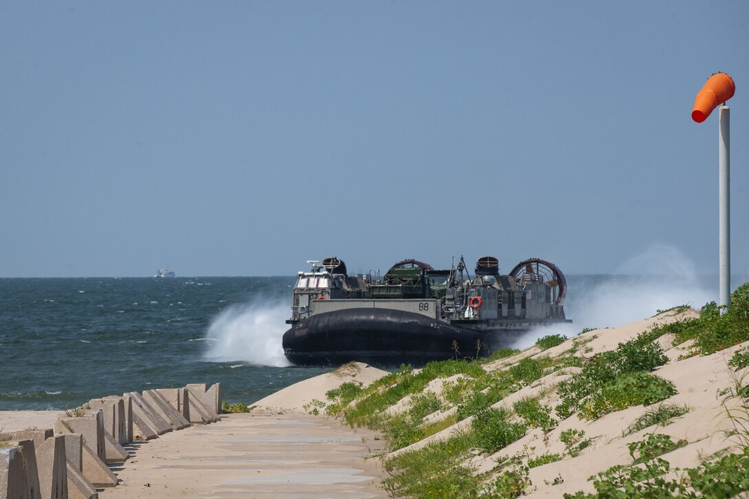 A U.S. Navy landing craft, air cushion lands on a beach while carrying tactical vehicles during Defense Support of Civil Authorities (DSCA) mission rehearsals at Naval Base Norfolk, Virginia, July 22, 2021. Marines and Sailors with the II Marine Expeditionary Force Maritime DSCA Task Force, commanded by Combat Logistics Battalion 22, and Sailors aboard the USS Arlington conducted a destructive weather mission rehearsal loading exercise to prepare and rehearse for a future DSCA mission during the 2021 hurricane season. (U.S. Marine Corps photo by Lance Cpl. Scott Jenkins)