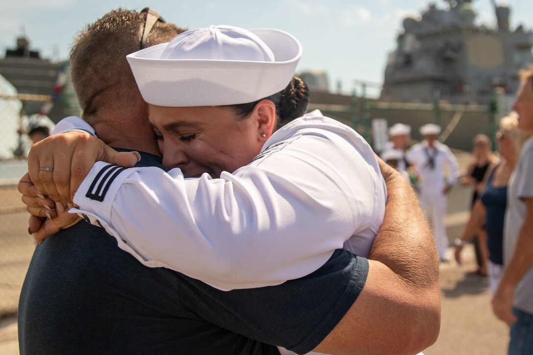 A sailor cries as she embraces her father.
