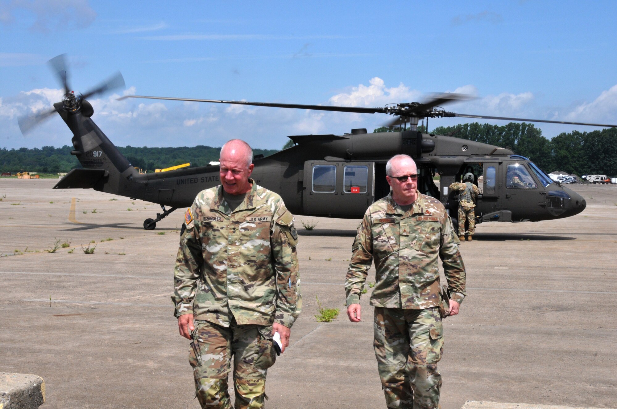 Two men in OCP Air Force uniform deboarding an helicopter.
