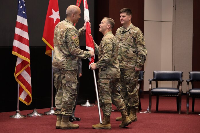 Maj. Gen. Jeffrey L. Milhorn, center, deputy commanding general for military and international operations of the U.S. Army Corps of Engineers, presents Huntsville Center’s colors to Col. Sebastien P. Joly on Friday, July 23, as Col. Marvin Griffin, outgoing commander, looks on. (Photo by Michael May)