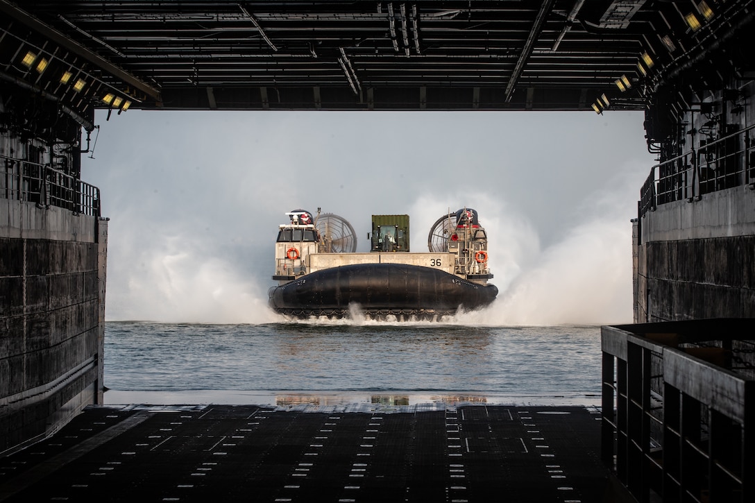 A U.S. Navy landing craft, air cushion is marshaled into the USS Arlington (LPD-24) carrying tactical vehicles during Defense Support of Civil Authorities (DSCA) mission rehearsals at Naval Base Norfolk, Virginia, July 21, 2021. Marines and Sailors with the II Marine Expeditionary Force Maritime DSCA Task Force, commanded by Combat Logistics Battalion 22, and Sailors aboard the USS Arlington conducted a destructive weather mission rehearsal loading exercise to prepare and rehearse for a future DSCA mission during the 2021 hurricane season. (U.S. Marine Corps photo by Lance Cpl. Scott Jenkins)