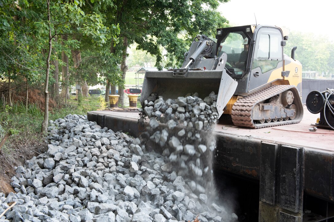 Dale Raines, U.S. Army Corps of Engineers Nashville District chief engineer assigned to the Iroquois, applies riprap July 22, 2021 along the shoreline of Old Hickory Lake to mitigate erosion near the Rock Castle Slave Cemetery in Hendersonville, Tennessee. The U.S. Army Corps of Engineers Nashville District's Maintenance Support Team reshaped the embankment and laid down riprap July 19-22, 2021 where water had been undercutting the shoreline. (USACE Photo by Lee Roberts)