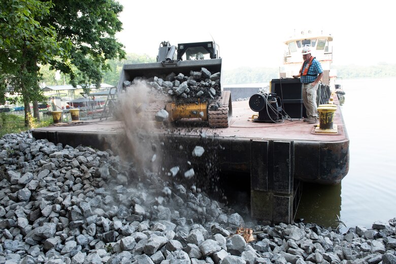 Herb Thomasson, master pilot of the Iroquois, watches as Dale Raines, U.S. Army Corps of Engineers Nashville District chief engineer assigned to the Iroquois, applies riprap July 22, 2021 along the shoreline of Old Hickory Lake to mitigate erosion near the Rock Castle Slave Cemetery in Hendersonville, Tennessee. The U.S. Army Corps of Engineers Nashville District's Maintenance Support Team reshaped the embankment and laid down riprap July 19-22, 2021 where water had been undercutting the shoreline. (USACE Photo by Lee Roberts)