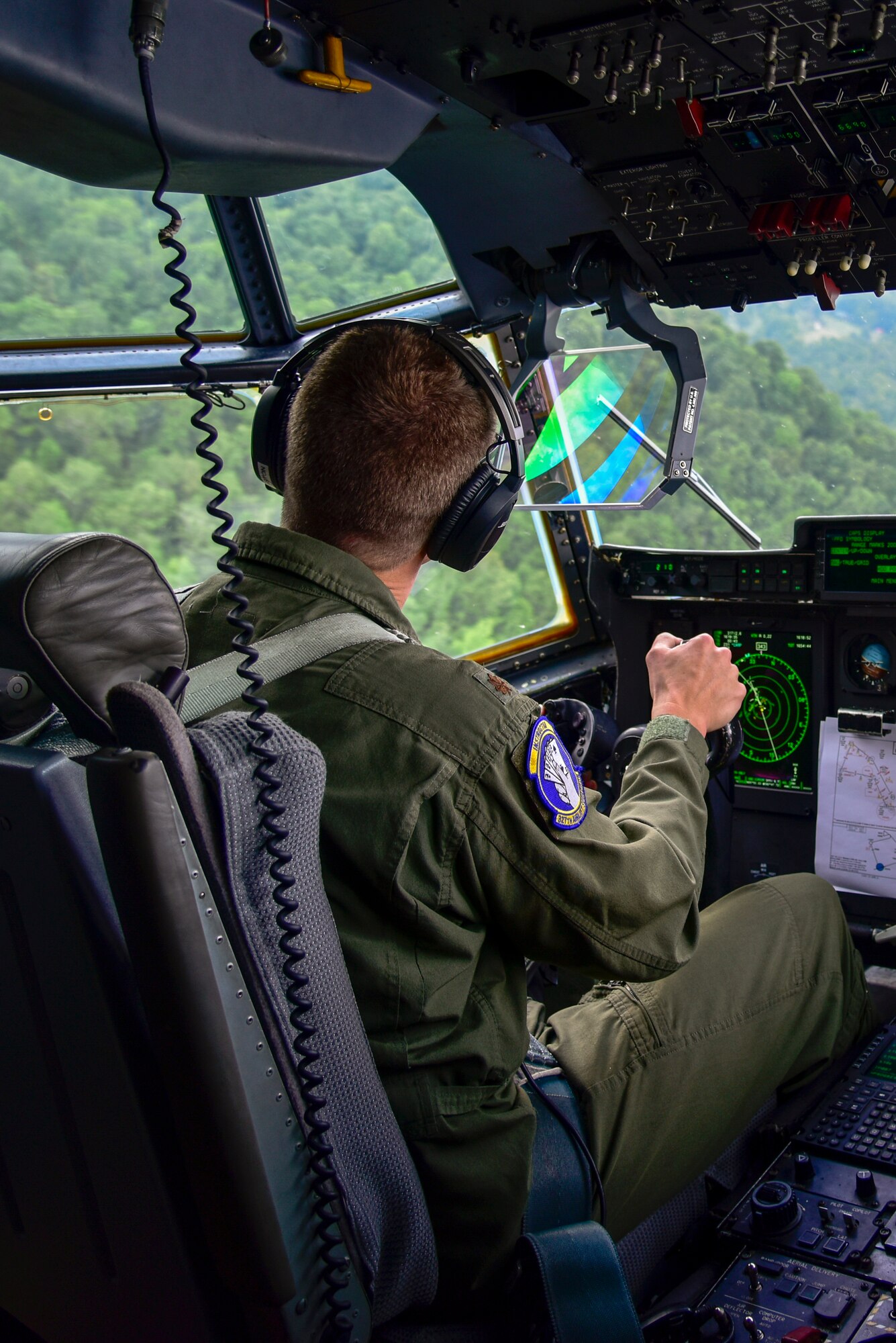Pilot in the cockpit flying over terrain.