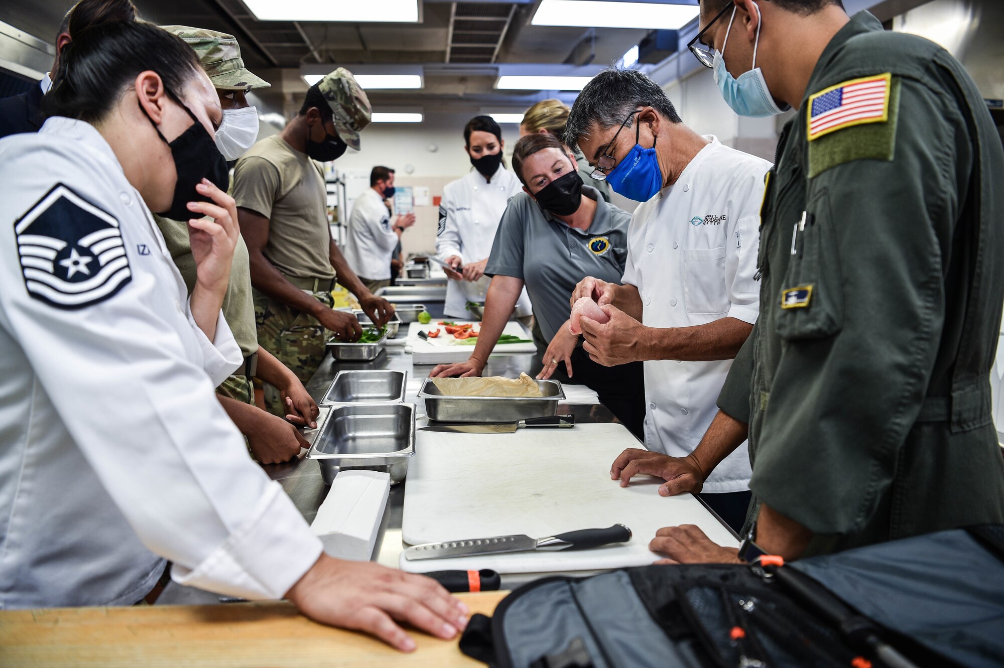 Celebrity chef, Roy Yamaguchi, instructs Airmen and Sailors during a visit to the Hale Aina Dining Facility on how to correctly prepare sashimi at Joint Base Pearl Harbor-Hickam, Hawaii, July 21, 2021. Three culinary teams, each having representatives from the 647th Force Support Squadron, the 65th Airlift Squadron, and the Commander, U.S. Pacific Fleet, participated in an unofficial cooking competition. (U.S. Air Force photo by Senior Airman Alan Ricker)
