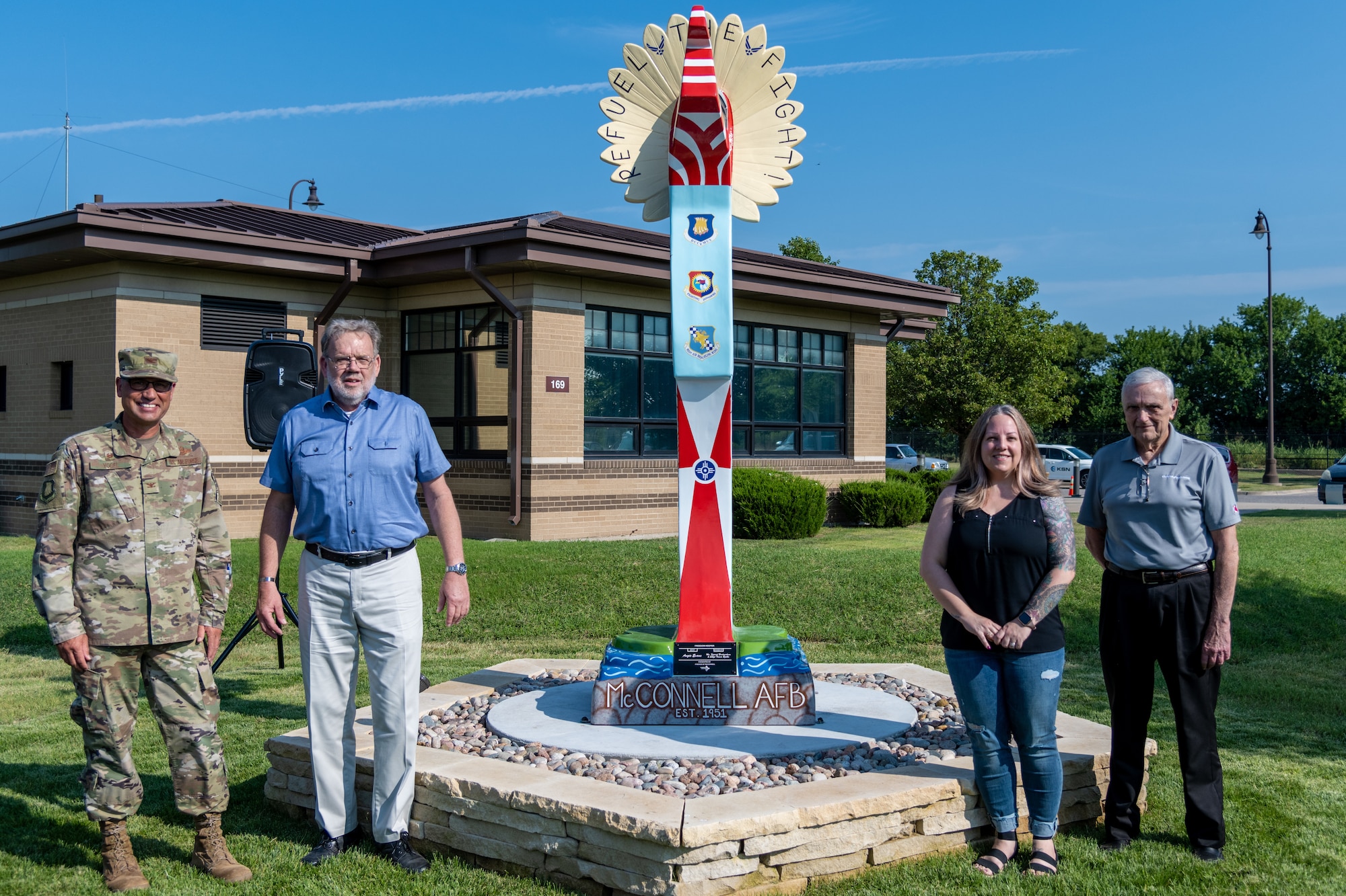 (From left to right) Col. Nate Vogel, 22nd Air Refueling Wing commander, Vincent Fredericksen, 22nd Civil Engineer Squadron base architect, Angie Evans, Wichita artist, and Jack Pulley, president of Friends of McConnell, pose for a photo next to the Keeper of the Plains replica donated to the base July 23, 2021, at McConnell Air Force Base, Kansas. The ten-foot-tall Keeper was donated by the Friends of McConnell organization and designed by Vincent Fredericksen, 22nd Civil Engineer Squadron base architect, and Staff Sgt. Trevor Bjelke, former 22nd Communications Squadron network infrastructure technician. (U.S. Air Force photo by Senior Airman Skyler Combs)