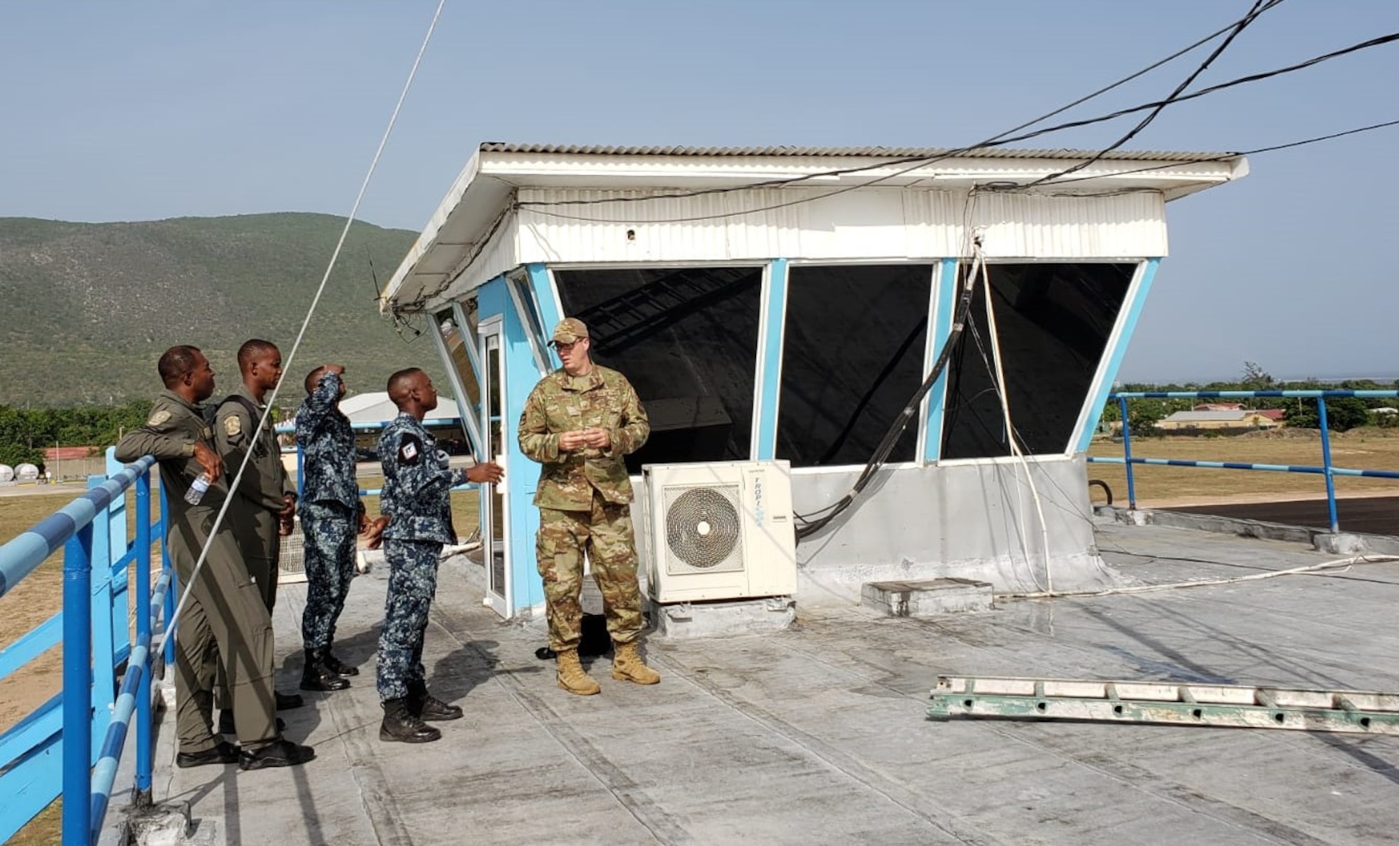U.S. Air Force Master Sgt. Joshua Miles, 571st Mobility Support Advisory Squadron air advisor, and Jamaican Defense Force Air Wing personnel, discuss radio antenna maintenance procedures at an airfield control tower in Up Park Camp, Kingston, Jamaica, June 17, 2021. Air advisors with the 571st MSAS spent weeks training JDF-AW forces on topics such as radio etiquette, maintenance, aircraft mishap and water survival. (Courtesy photo)