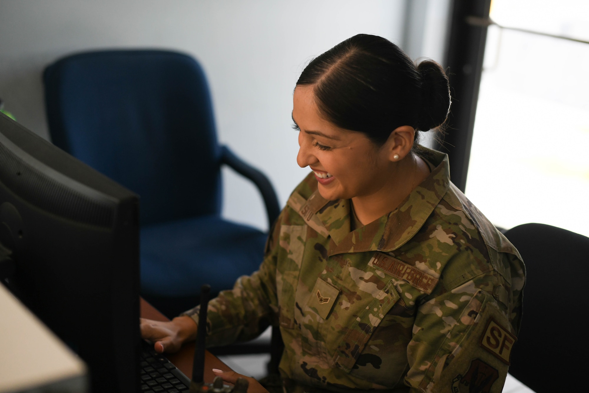 Airman 1st Class Jocelyn Soto smiles as she types on a computer.