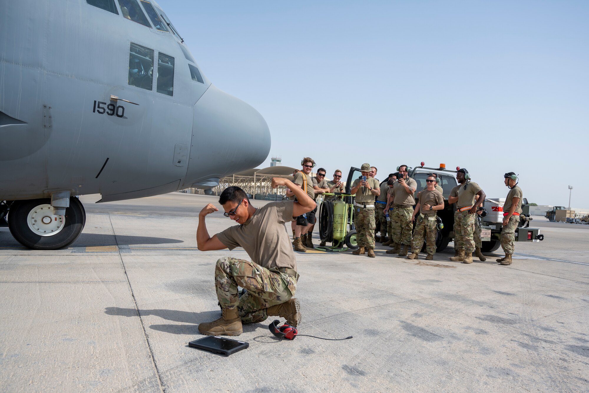 Airman flexing muscles in front of a group of Airmen