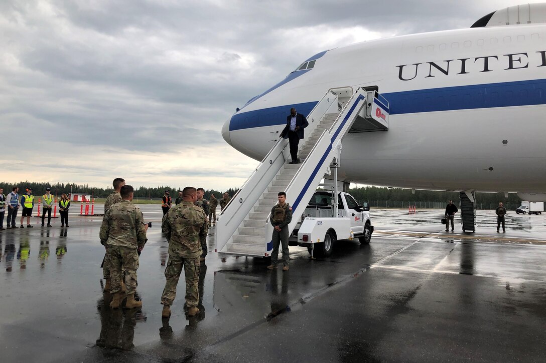 A man walks down some stairs that are outside the door of a plane.