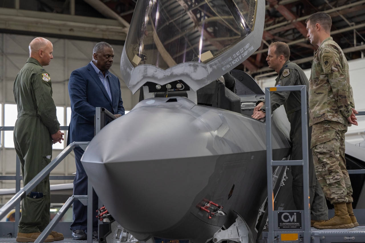 Four men stand around a military aircraft.