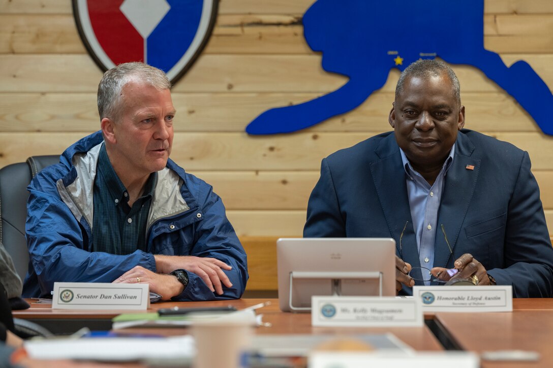 Two men sit next to each other at a table.