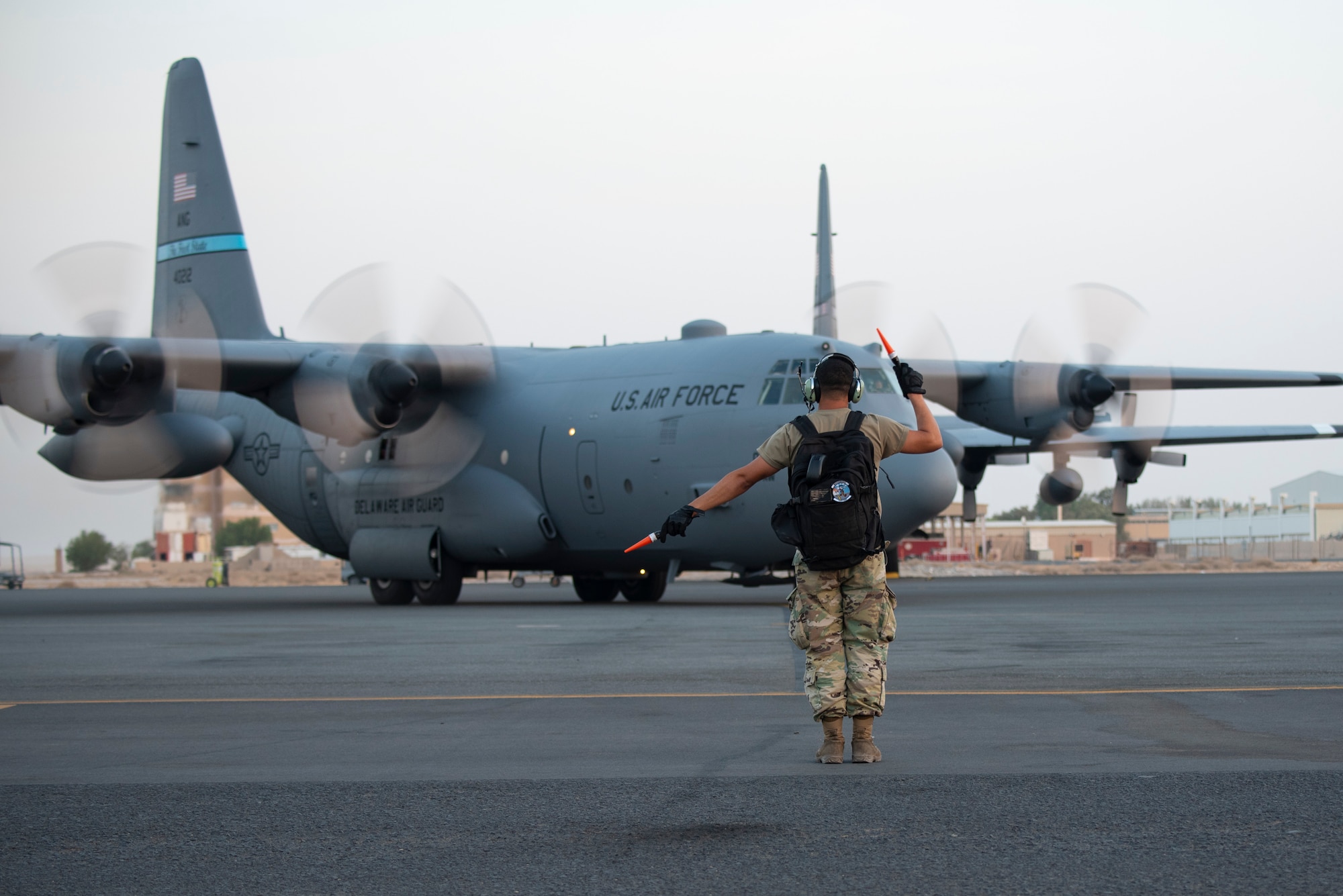 A U.S. Air Force crew chief assigned to Ali Al Salem Air Base, Kuwait, marshals in a C-130 Hercules July 20, 2021. The EAMXS works 24-hour operations year-round to keep the C-130 Hercules’ in flight to accomplish the mission of fight to win today and to provide warfighter support in the area of responsibility. (U.S. Air Force Photo by Senior Airman Helena Owens)