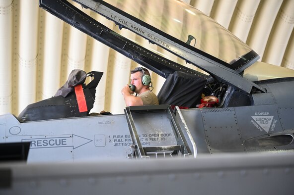 An Airman sitting in an airplane tests communications systems.