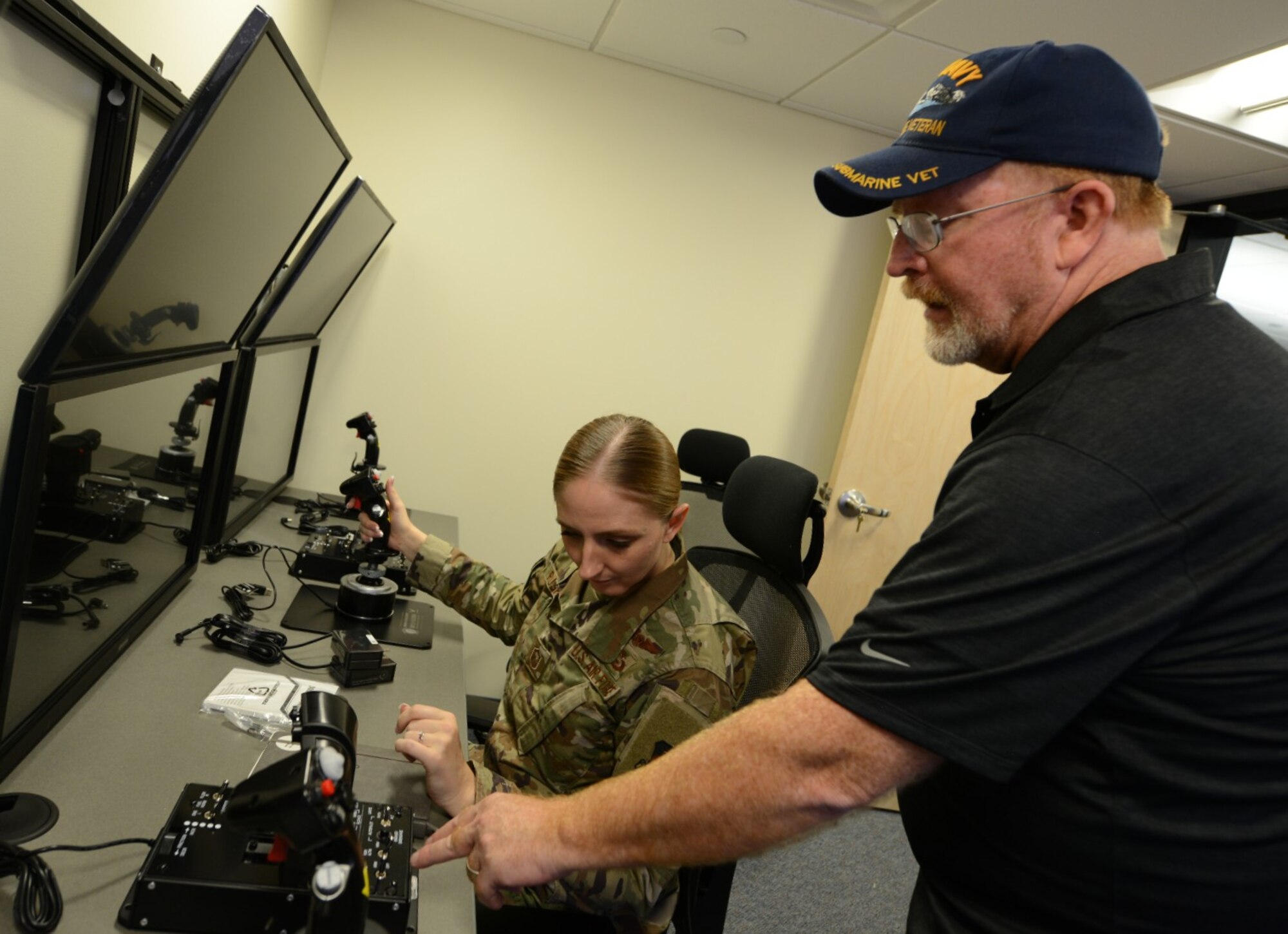 Red Hoar, a software development program manager, teaches Master Sgt. Bonnie Rushing, a military and strategic studies instructor at the U.S. Air Force Academy, to operate the remotely piloted aircraft control room in the school’s multi domain laboratory, July 22, 2021.