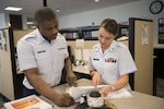 ARLINGTON, Va. - A Coast Guard yeoman assists a fellow Coast Guardsman at the Coast Guard Recruiting Command, February 20, 2013. YNs are key problem-solvers, counselors, and sources of information to personnel on questions ranging from career moves, entitlements, and incentive programs to retirement options and veterans' benefits. U.S. Coast Guard photo by Petty Officer 1st Class Luke Pinneo