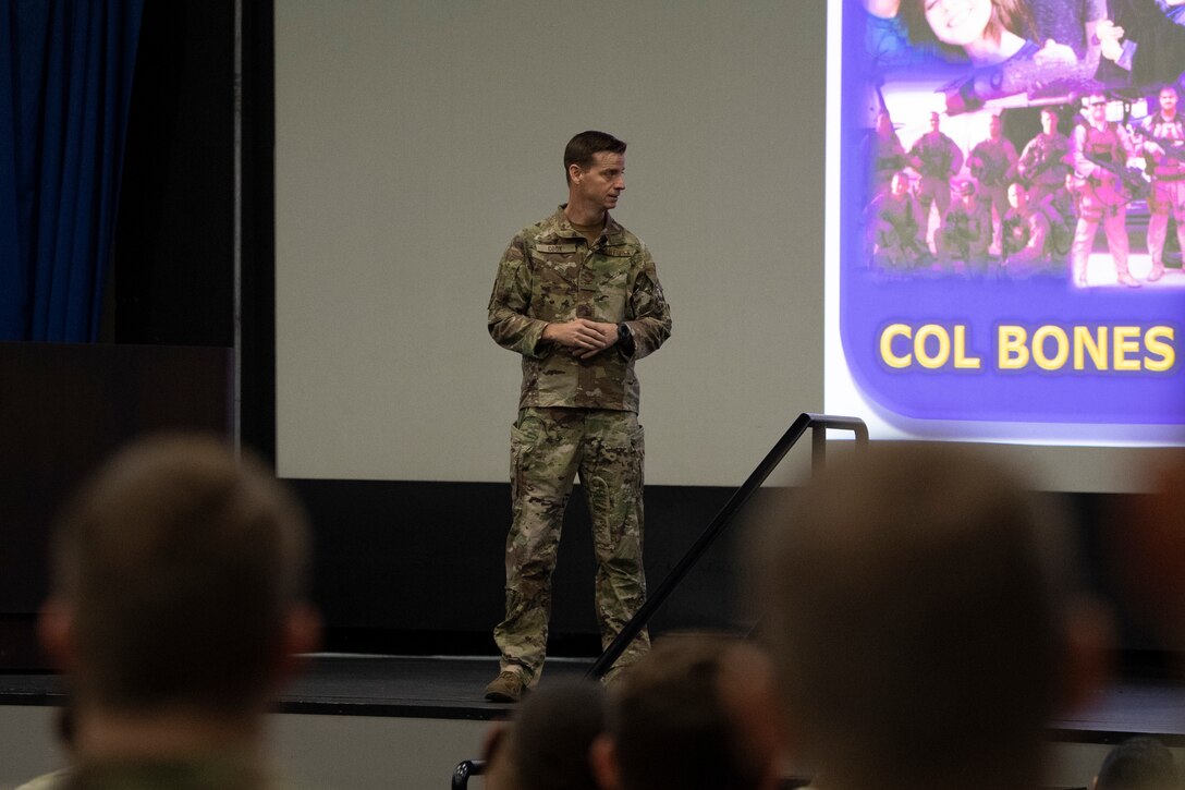 A photo of an Airman standing on a stage in an auditorium.