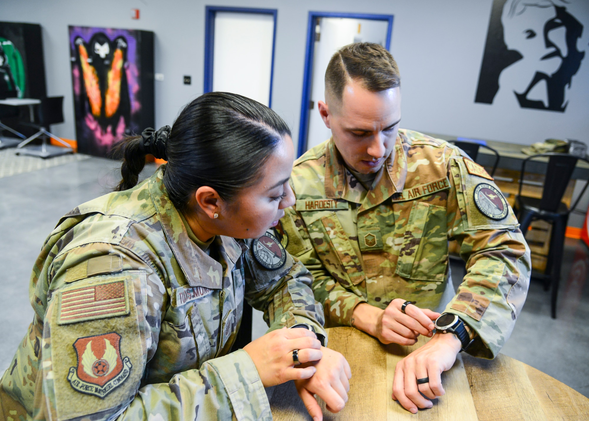 Master Sgt. Chad Hardesty, Ellington Airman Leadership School commandant, and Tech. Sgt. Carmen Turcios Munoz, ALS instructor, compare biometric data from their smartwatches at Edwards Air Force Base, California. The watches provide Airmen biofeedback to improve physical exercise, their sleep, their timing of when to tackle which tasks and other benefits. (Air Force photo by Gary Hatch)